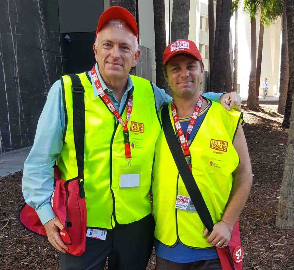 Peter Schmidt, partner at Norton Rose Fulbright, sells magazines with vendor Gary in Brisbane