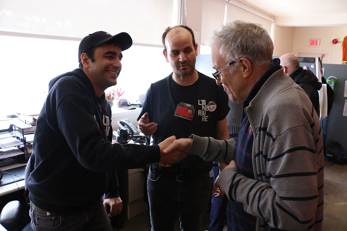 Vendor Mostapha introduces a visitor to L’Itinéraire artistic director and graphic artist Milton Fernandes. Photo: Mario Alberto Reyes Alberto.