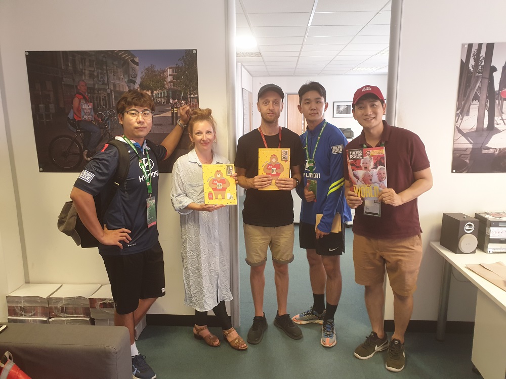 Big Issue (UK) staff based in the Cardiff office Lotty Talbutt and Tom Watts, flanked by representatives from The Big Issue Korea visiting while in the city for the 2019 Homeless World Cup.