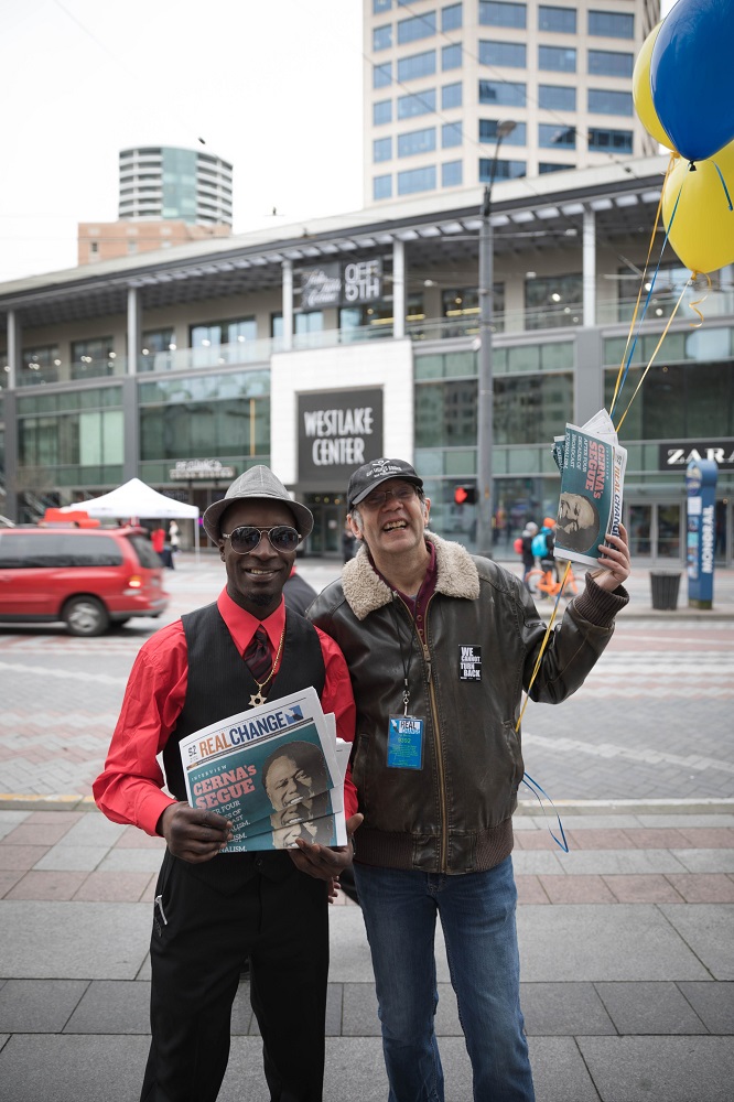 Real Change Founding Director Tim Harris (right) sells copies of Real Change alongside vendor Darryl Manassa (left) for vendor week during Feb. 2018. Photo by Sam Holman.