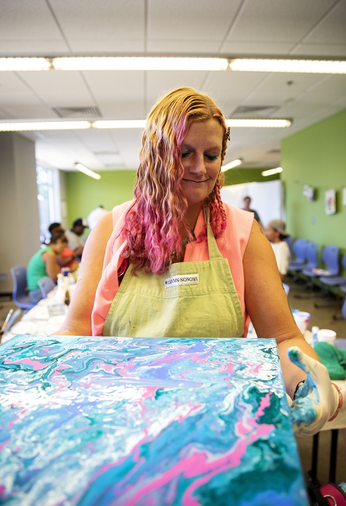 Lauren puts the finishing touches on her acrylic drip painting. She learned the technique from a YouTube video. [Credit: Nathan Poppe]