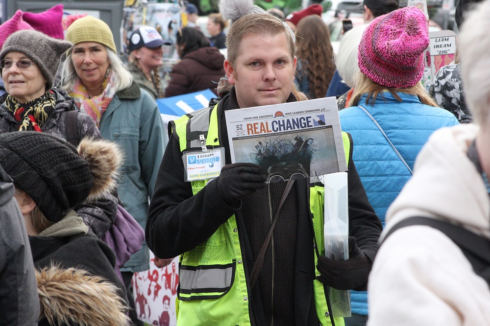 Real Change Vendor James Jenkins selling papers at the 3rd Annual Womxn's March in Cal Anderson Park Saturday, Jan. 19. Photo by Jon Williams.