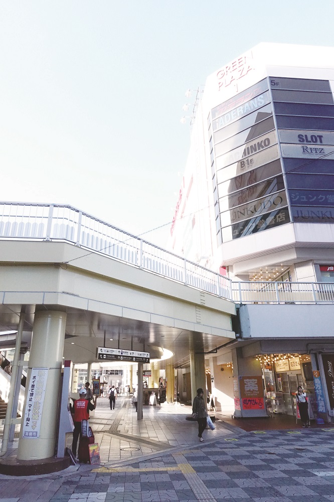 Mr K. sells the street paper below the south side escalator on the south exit’s deck of the Takatsuki JR station in Osaka. [Credit: Yoshihiro Kinoshita]