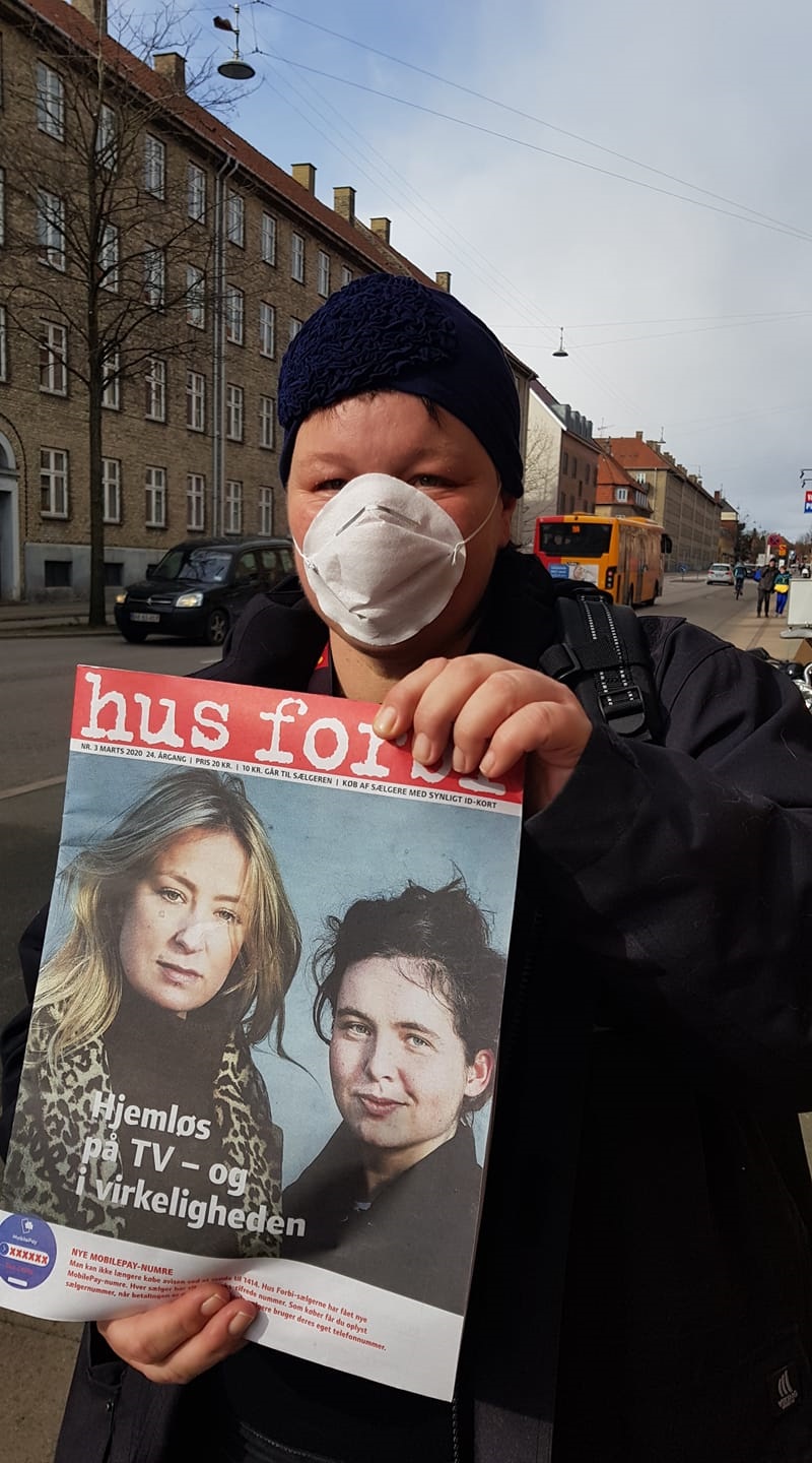 A Hus Forbi vendor sells the street paper while protecting herself with a face mask.