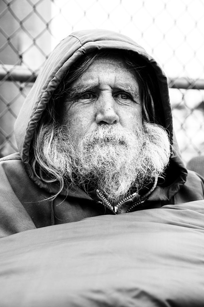 Jim kept warm under a sleeping bag on a freezing cold April 2 morning. He rarely leaves his camp and has been struggling with not being able to secure a bed at night. [Credit: Nathan Poppe]