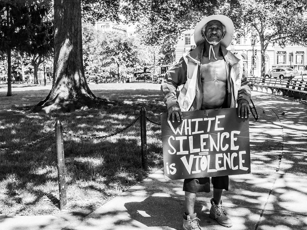 Moon - homeless in DC - with a sign for protest. [Credit: Benjamin Burgess / K Street Photography / Street Sense]
