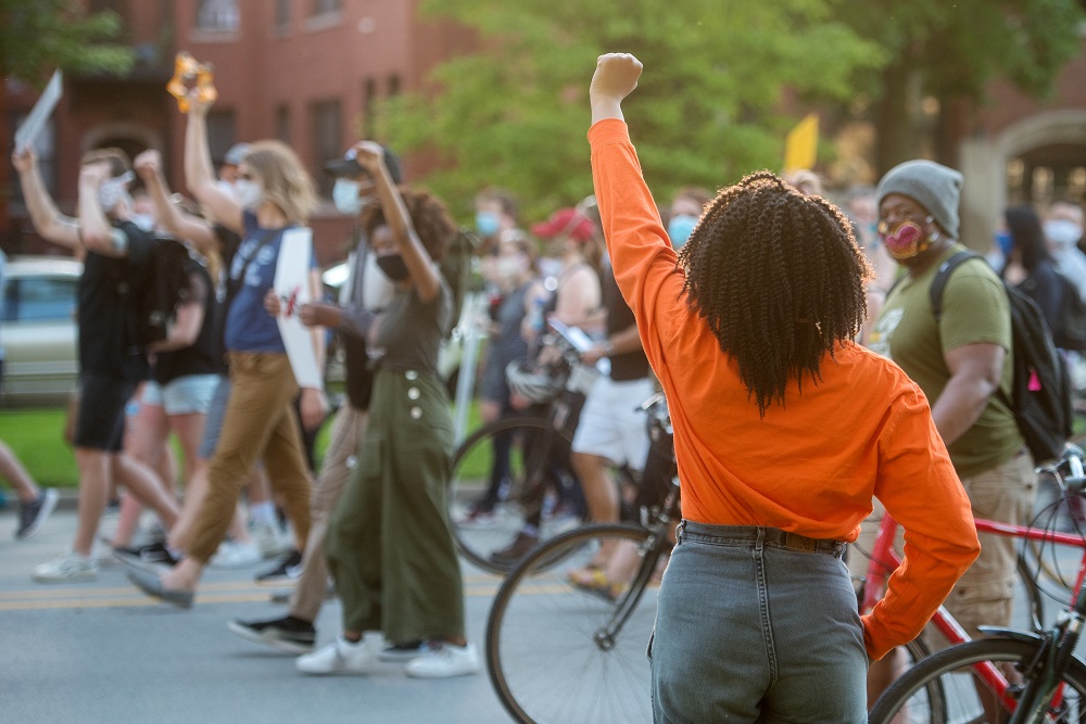A woman holds her fist in the air as thousands march peacefully down Martin Luther King Drive. [Credit: Kathleen Hinkel/StreetWise]