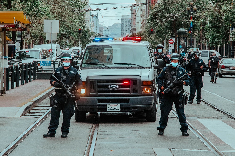 Police armed with rubber bullet weapons stand at the edge of a protest on Market Street. [Credit: Kit Castagne]