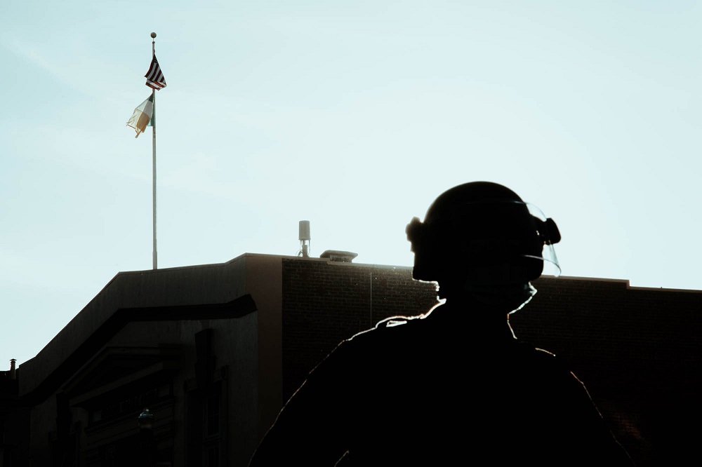 A police officer stands in a closed off 17th street as protesters gather around the Mission police station. [Credit: Kit Castagne]