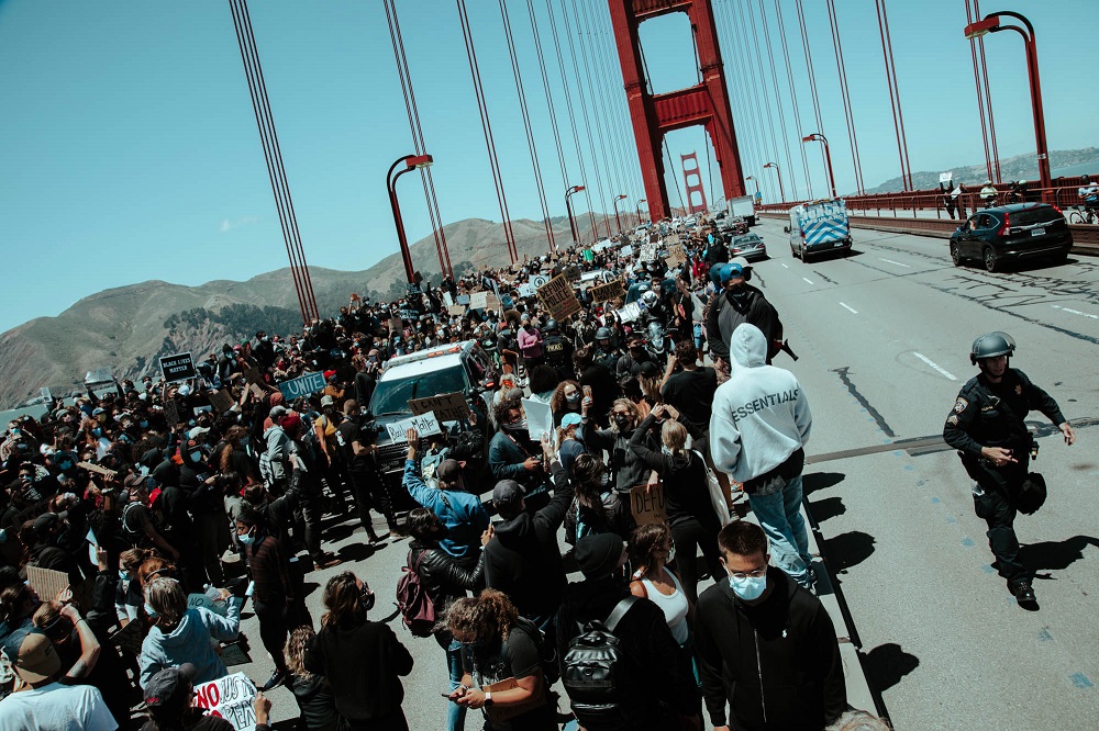 A police officer rushes to communicate with fellow officers as an increasing number of protesters gather in the Golden Gate Bridge roadway. [Credit: Kit Castagne]