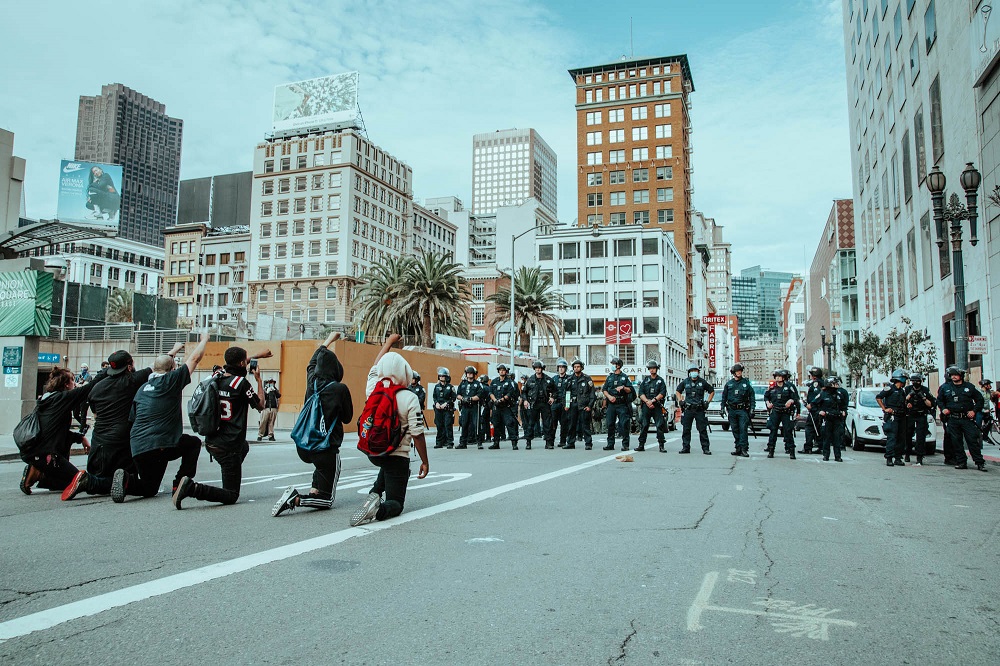 Protesters kneel in front of a line of police in Union Square. [Credit: Kit Castagne]