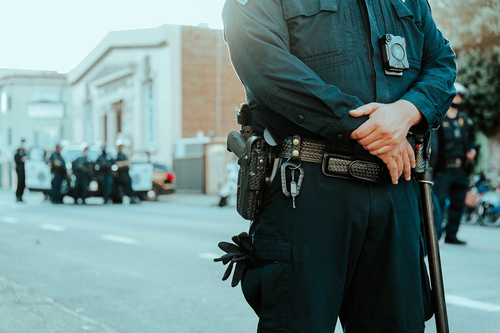 Police wait outside the Mission police station as the city’s curfew draws near. [Credit: Kit Castagne]