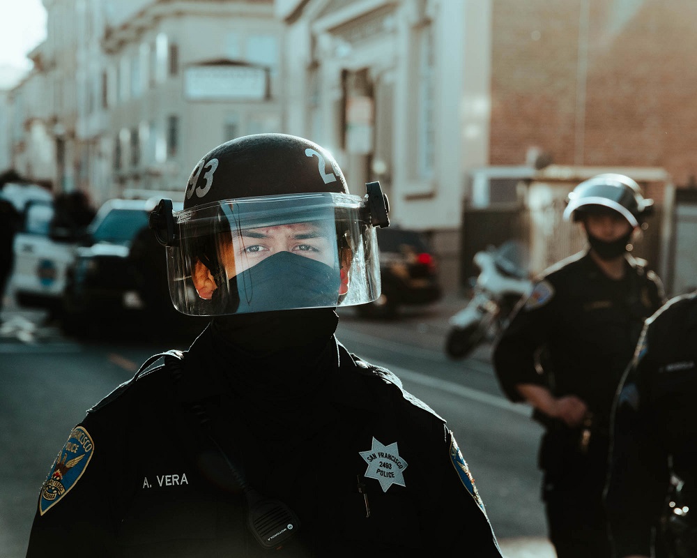 A police officer watches protesters from behind a barrier on 17th street. [Credit: Kit Castagne]