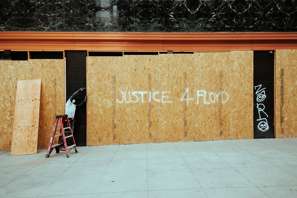 The morning after widespread looting in Union Square, a worker covers the windows of Macy’s with plywood. [Credit: Kit Castagne]