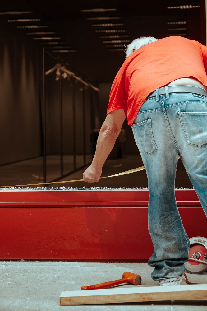 A worker clears glass from, and installs plywood over the broken windows of Acne Studios on Geary Street. [Credit: Kit Castagne]