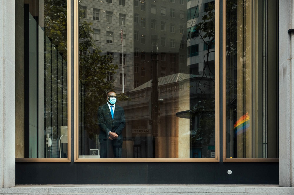 A man watches protesters march past from within an office building on Market Street. [Credit: Kit Castagne]