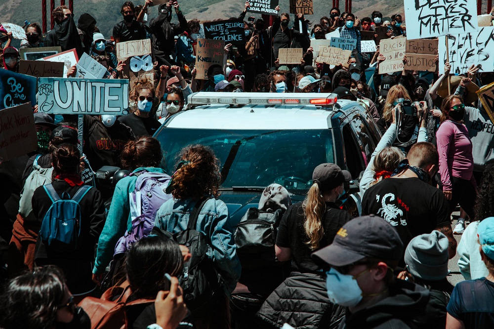 Protesters encircle a police car on the Golden Gate Bridge. [Credit: Kit Castagne]