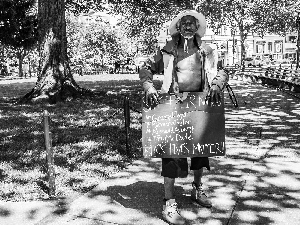 Moon - homeless in DC - with a sign for protest. [Credit: Benjamin Burgess / K Street Photography]