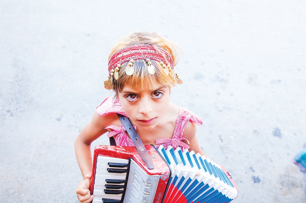 Romani girl playing the accordion in the street at the Guča Trumpet Festival in Serbia in 2014.