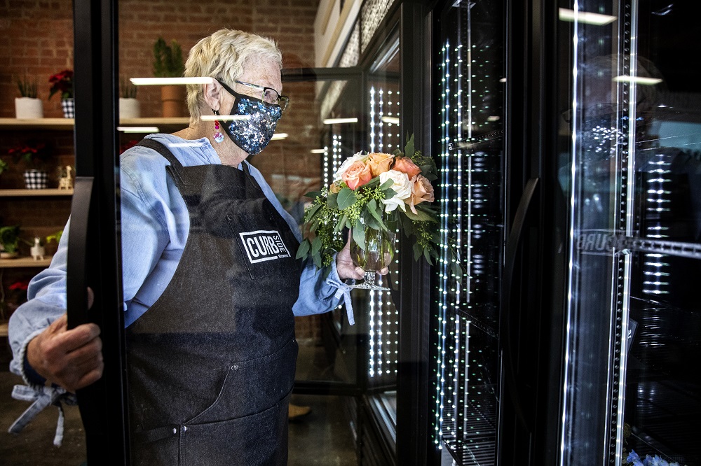 Marsha places a bouquet in the display fridge. [Credit: Nathan Poppe, The Curbside Chronicle]