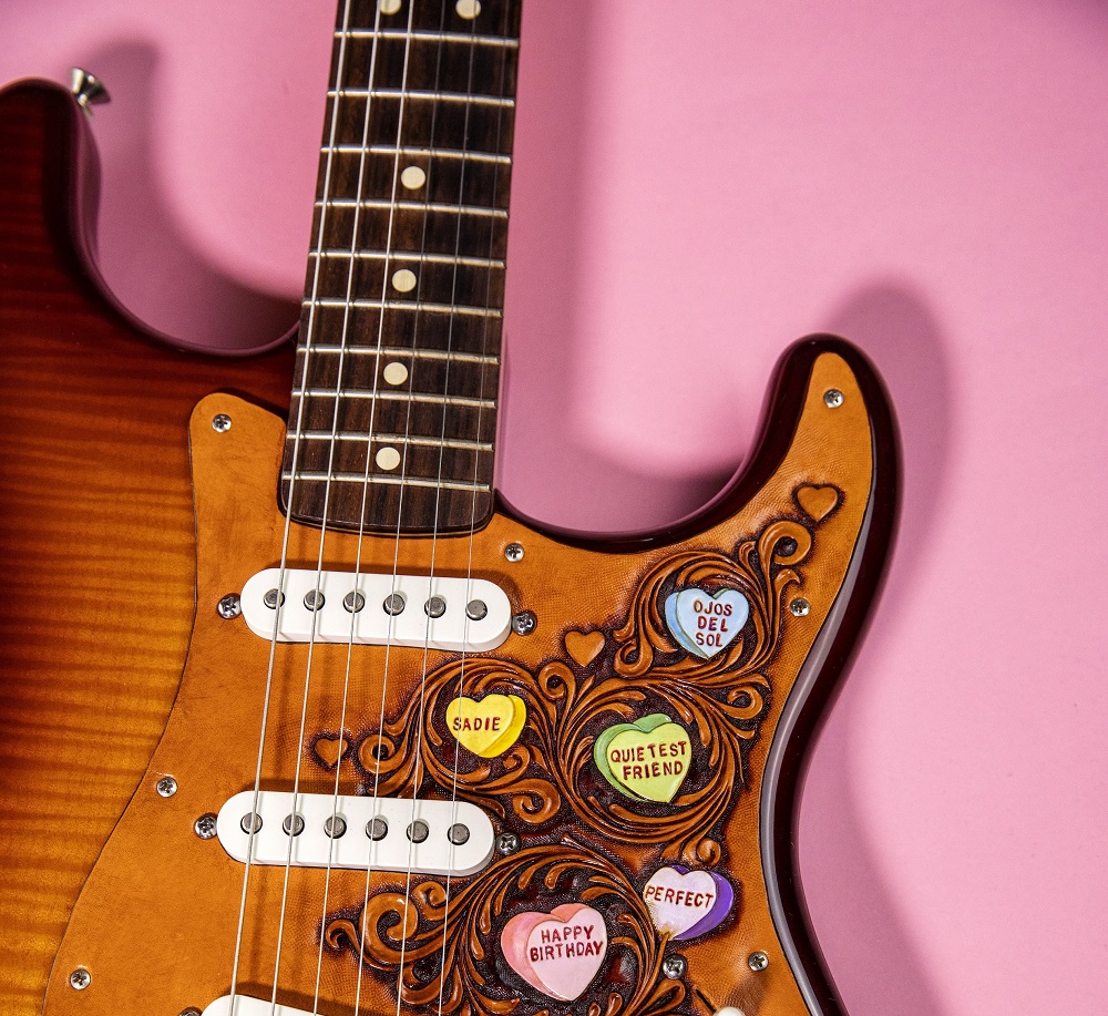 Oklahoma-based musician and artist Ali Harter created a custom leather guitar pickguard with song titles from the story in candy hearts. [Photo by Nathan Poppe, The Curbside Chronicle]